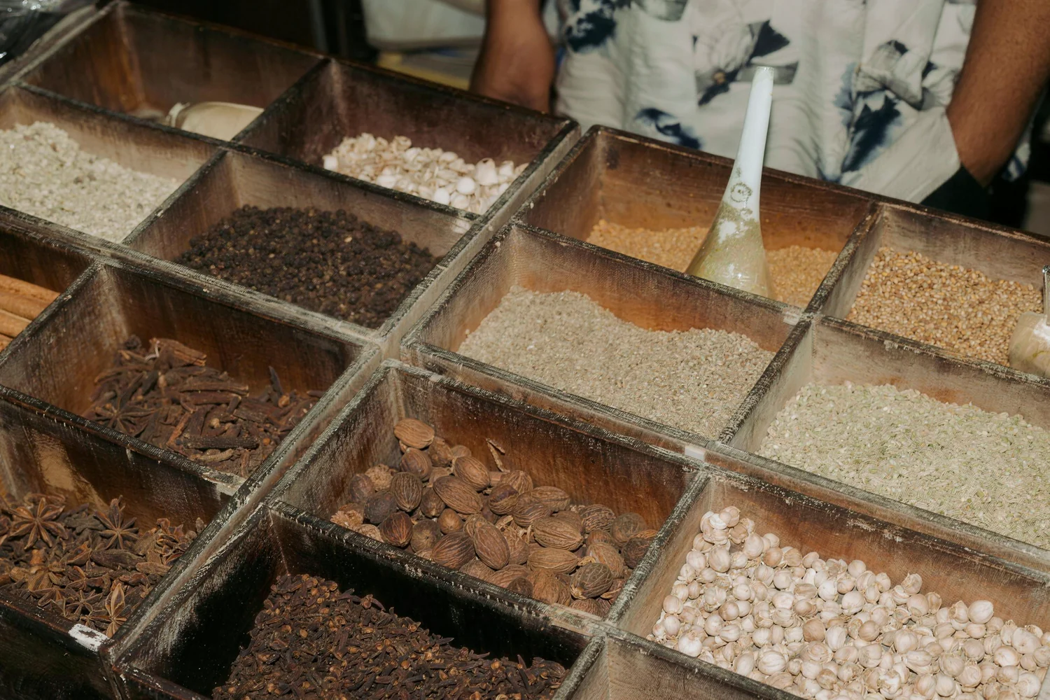 Wooden trays of spices and dried seeds at a Chiang Mai market